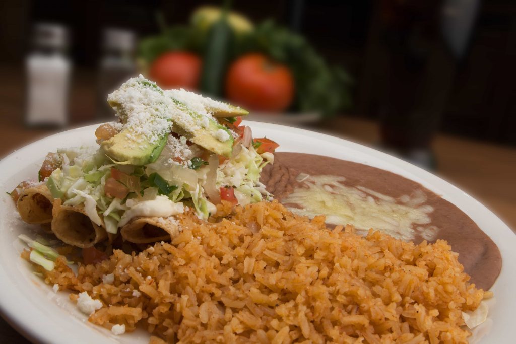 Taquito dinner featured with rice and refried beans on the side