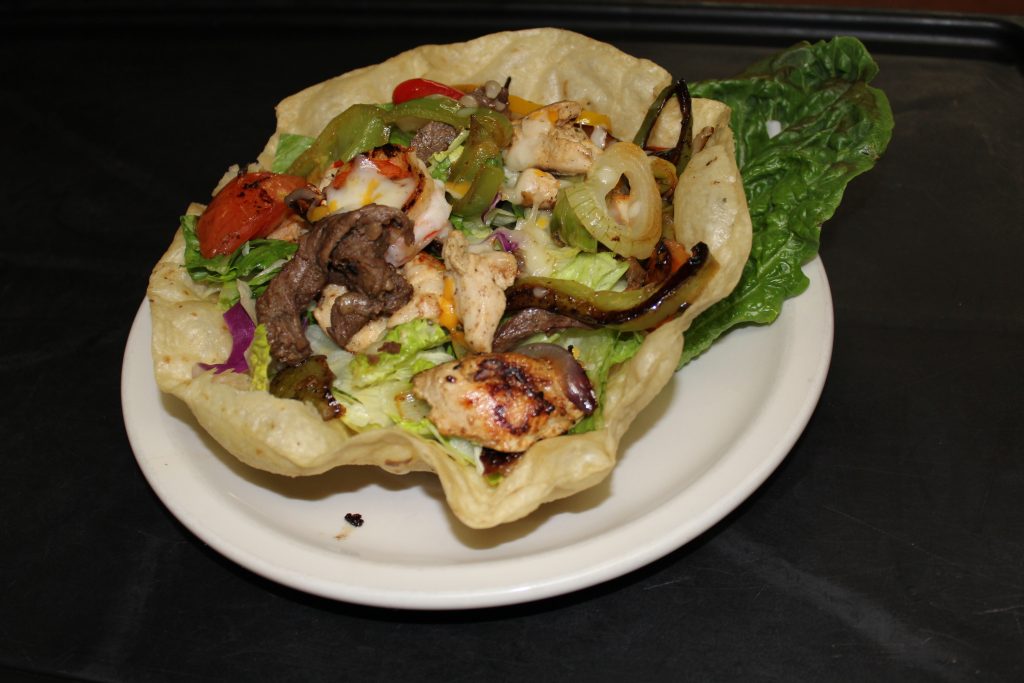 Fiesta salad in a crunchy shell with carne asada and chicken