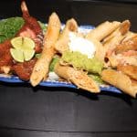 An appetizer plate with quesadillas, poppers, lime, avocado, and tomatoes